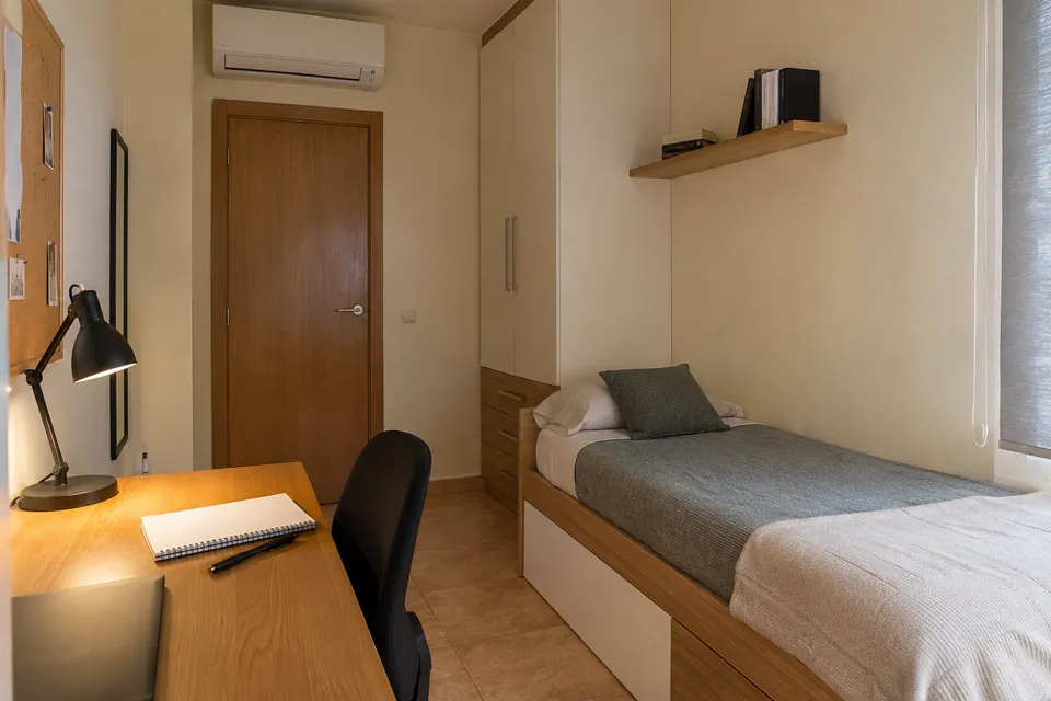 Dormitorio con escritorio y aire acondicionado sobre la puerta